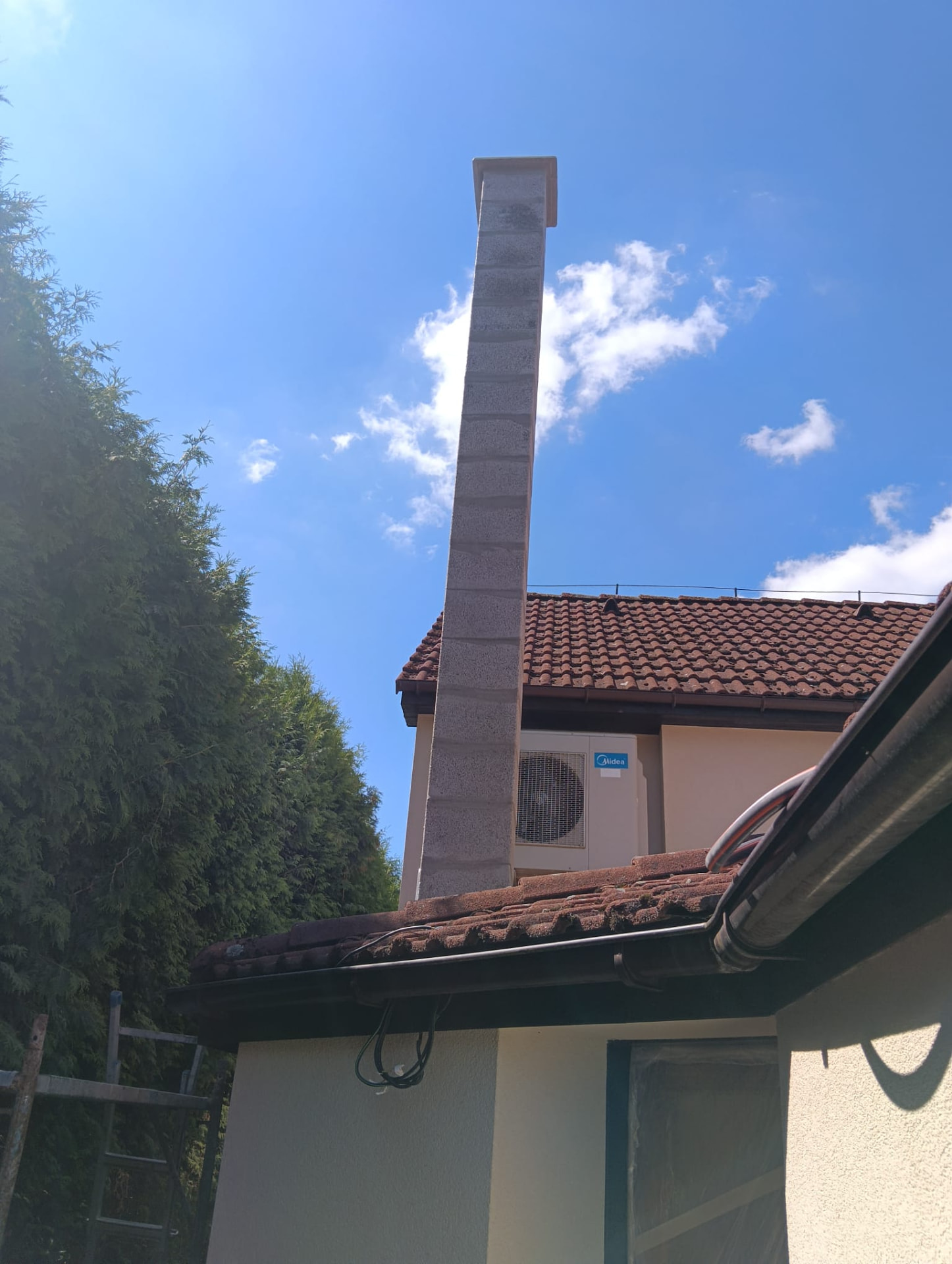 Dokončený komín vyvedený nad hřeben střechy rodinného domu